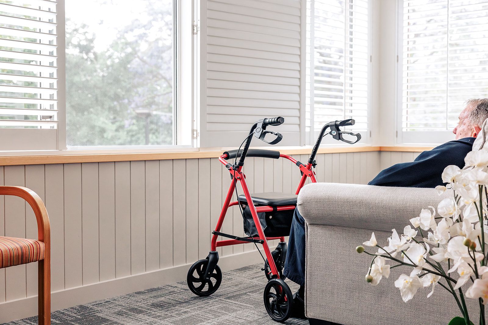 A cosy corner in a St Catherine’s room with a red mobility walker beside a sofa, showing comfortable and accessible living