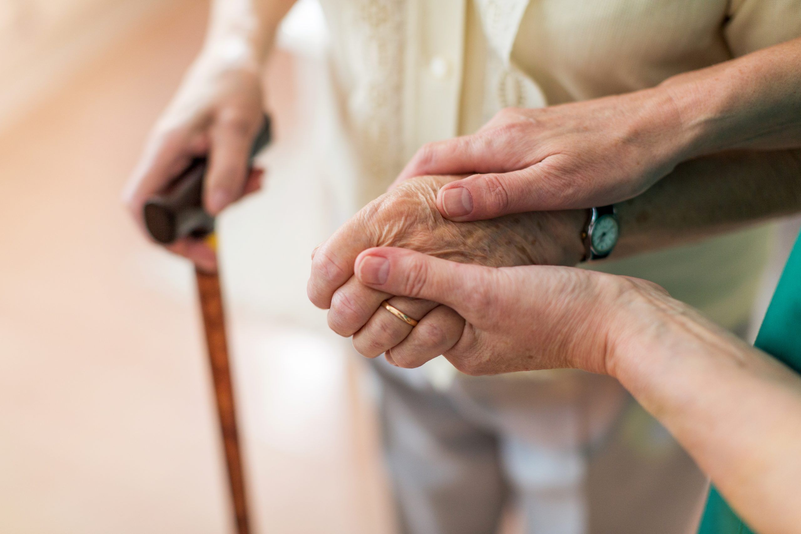 A younger hand gently holding an elderly hand, symbolising care and support for Respite Day Care services.